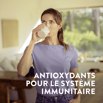 Une femme buvant un verre d'Assure avec un texte sur l'image soulignant les antioxydants pour le soutien de l'immunité