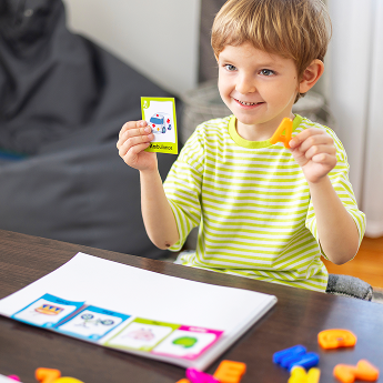 Un garçon montre qu'il apprend en tenant une carte avec la lettre A et une carte avec l'image d'une ambulance