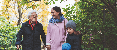 Old age, middle age and child together smiling on a walk in the forest with their coats on