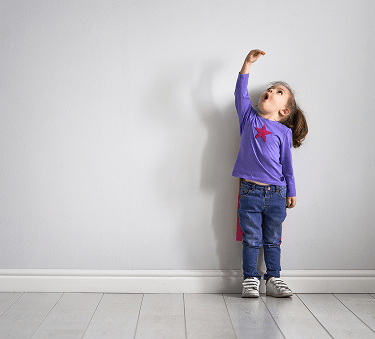 A young girl holds her hand high above her head showing surprise at her growth in height