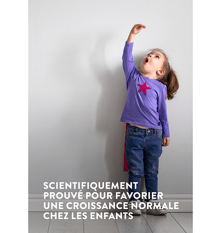 Une jeune fille portant un haut violet, la main levée, tente de mesurer sa taille avec le texte scientifiquement prouvé pour aider les enfants à grandir normalement.