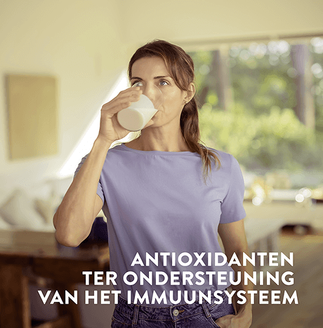 Een vrouw die een glas Ensure drinkt, met op de afbeelding tekst die de antioxidanten voor immuniteitsondersteuning benadrukt