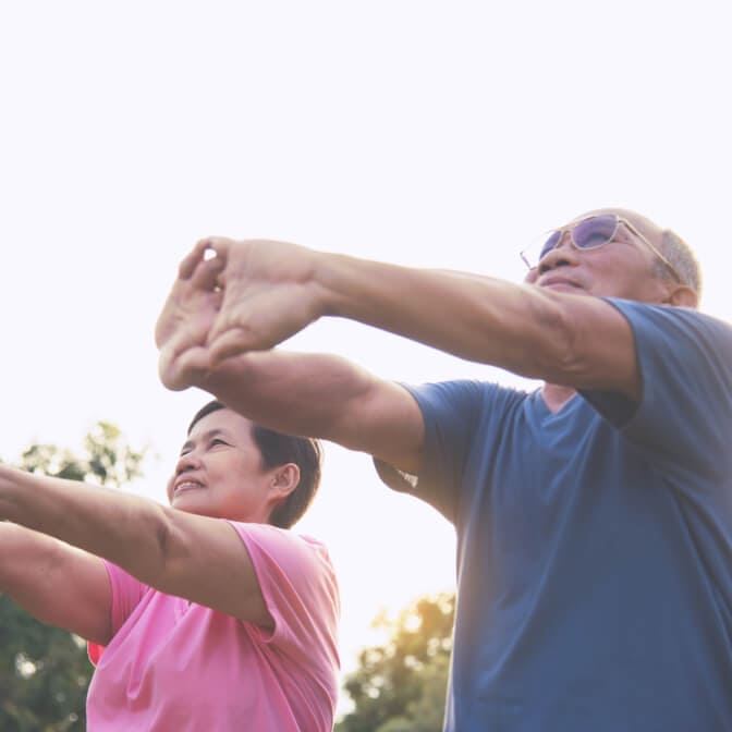 Elderly couple stretching their hands out
